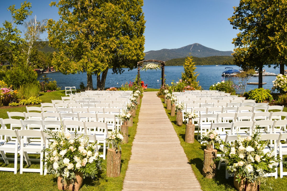 Wedding ceremony setup by a lake, with rows of white chairs and an arch, ideal for reducing tour no-shows.