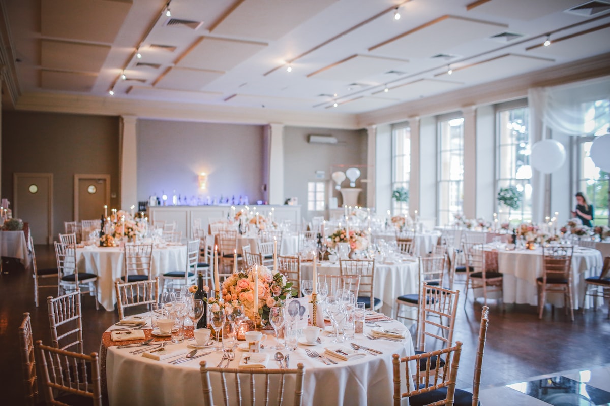 Wedding reception hall set up with tables, chairs, candles, and floral centerpieces